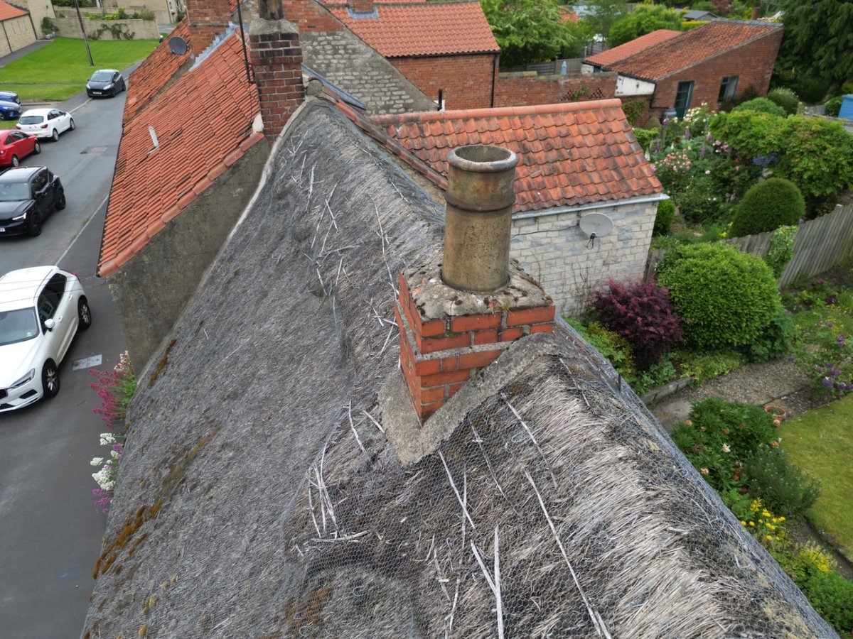 Weathered ridge and chimney interface to thatched roof